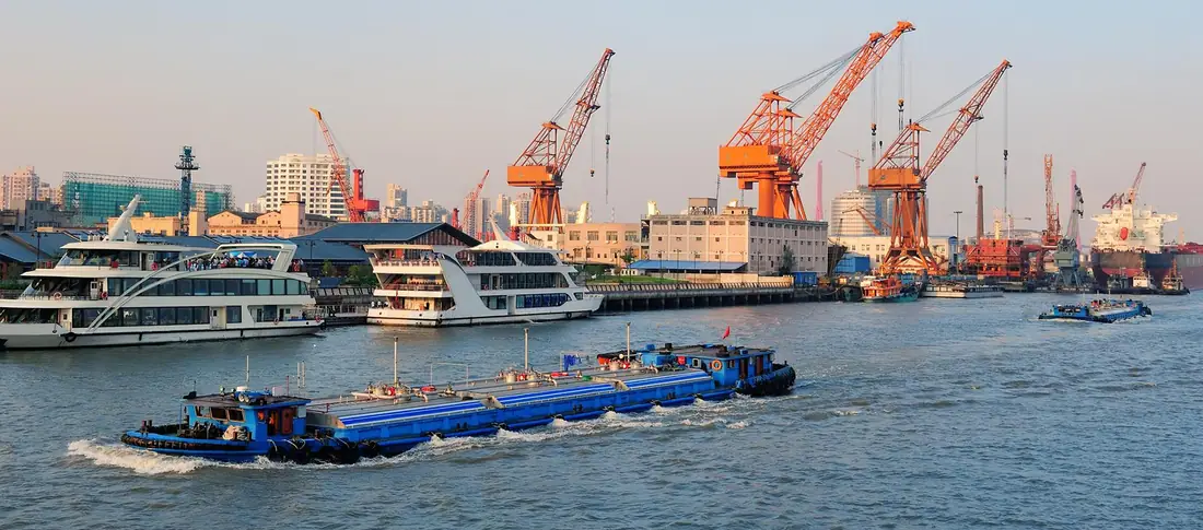 Port with quay cranes and a barge moving containers